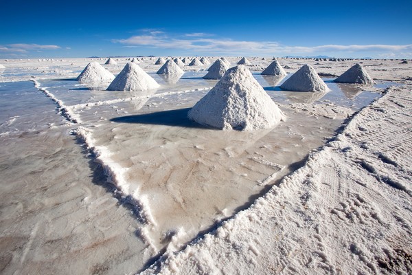The mining of salt by hand is practiced by locals in the Salar de Uyuni, Bolivia.  By using picks and shovels the salt is piled high into pyramids to drain the water.  Once dry it is shoveled into open bed trucks that take it a few kilometers to Colchani for further processing by hand and using antiquated machinery.
